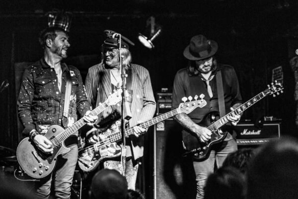 Moody black and white image of band Enuff Z'Nuff on stage playing at Bottom of the Hill in San Francisco, California. All members of the band are holding guitars.